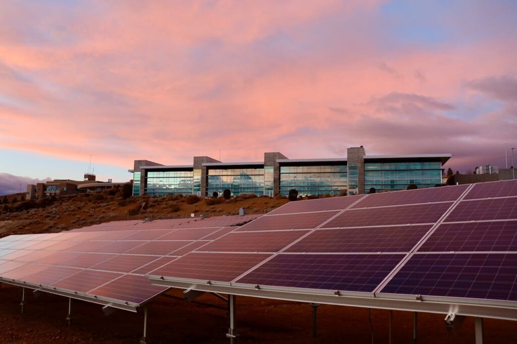 pexels-photo-6601008 Solar panels in front of a modern building at sunset showcasing renewable energy technology.
